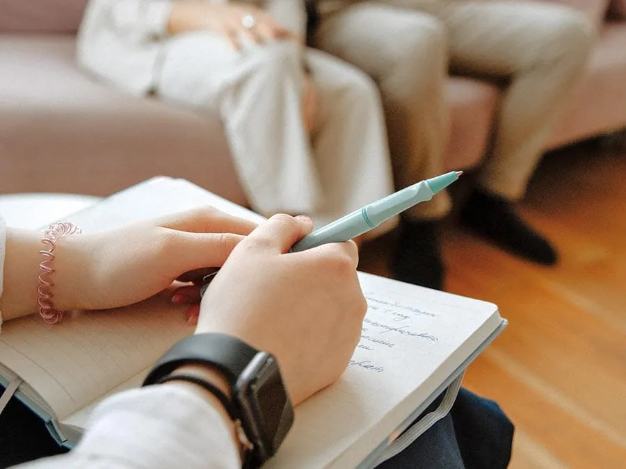 Close-up of therapist taking notes during couples counseling session, symbolizing guidance, communication, and relationship growth through therapy
